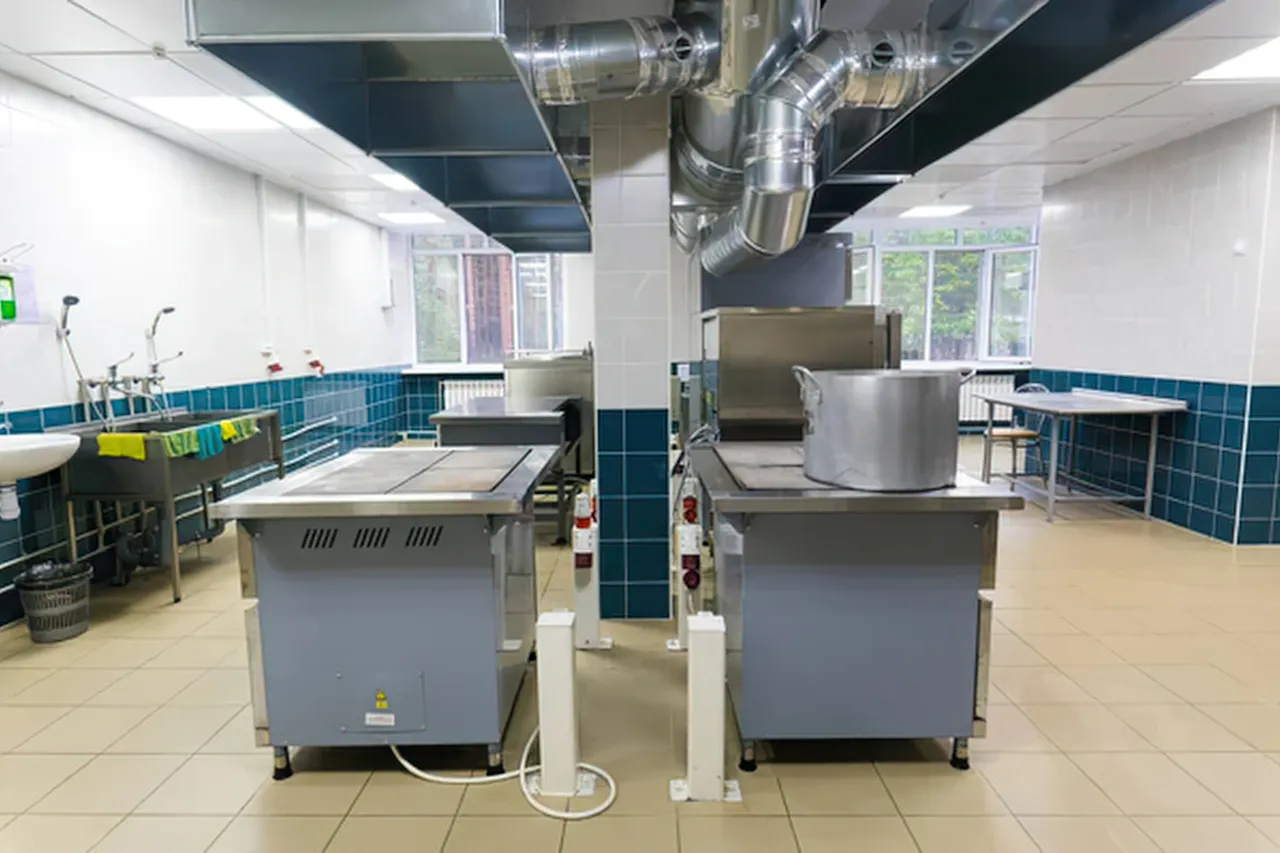 Cucina industriale con grandi pentole e cappe aspiranti