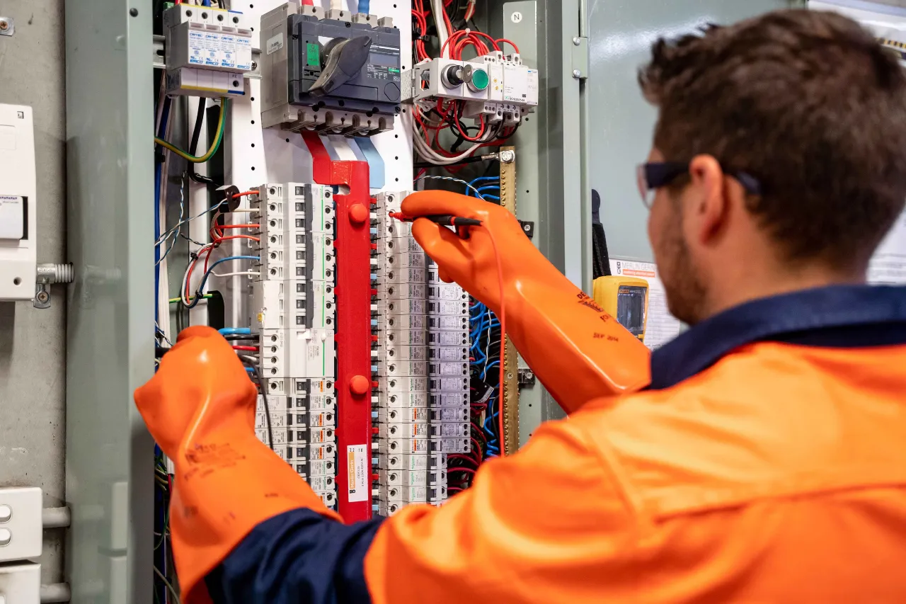 Tecnico verifica un quadro elettrico con guanti isolanti