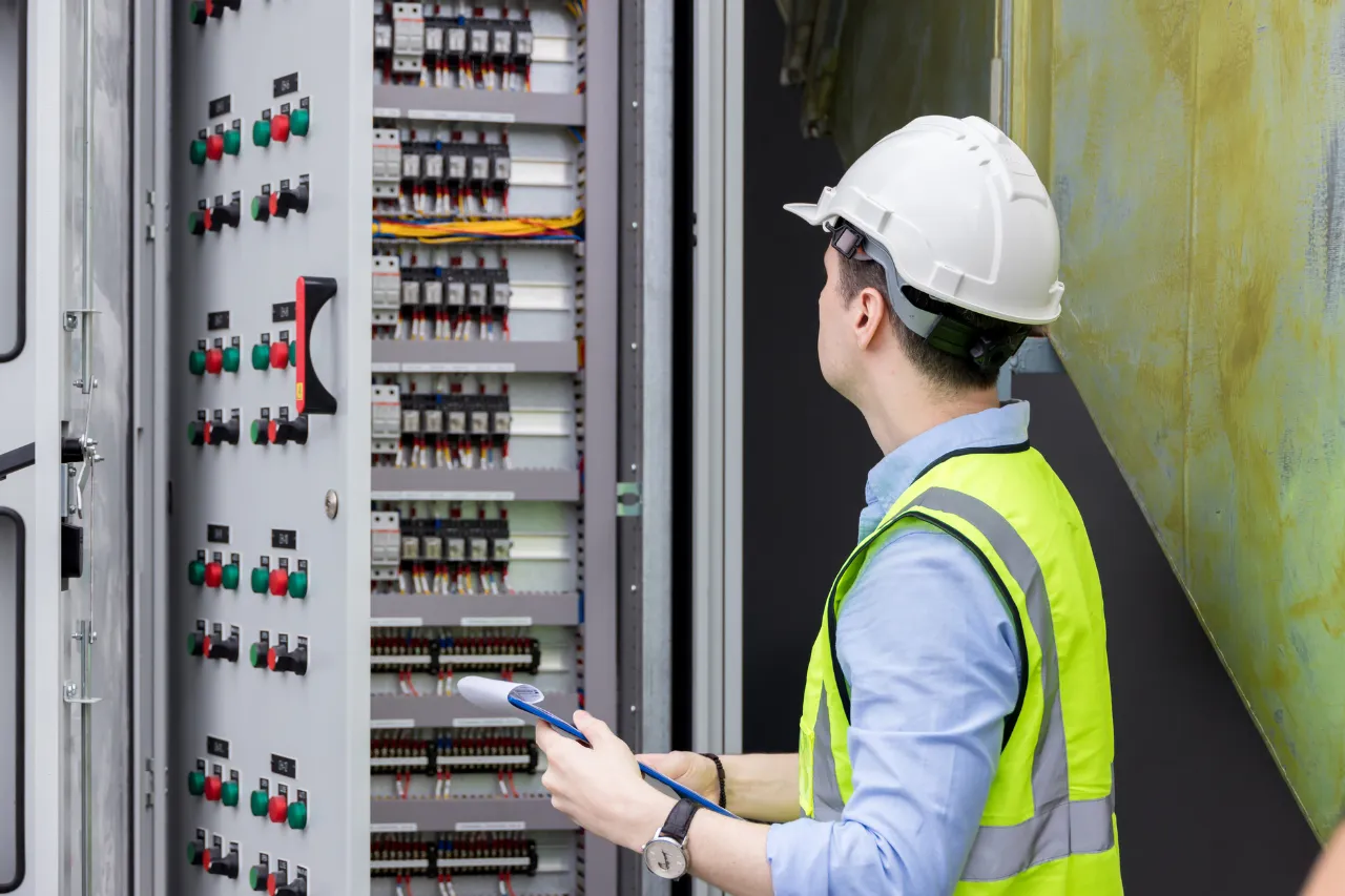 Tecnico controlla quadro elettrico industriale con casco