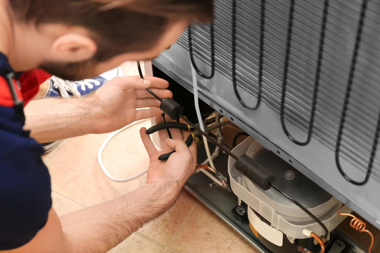 Tecnico ripara il retro di un frigorifero