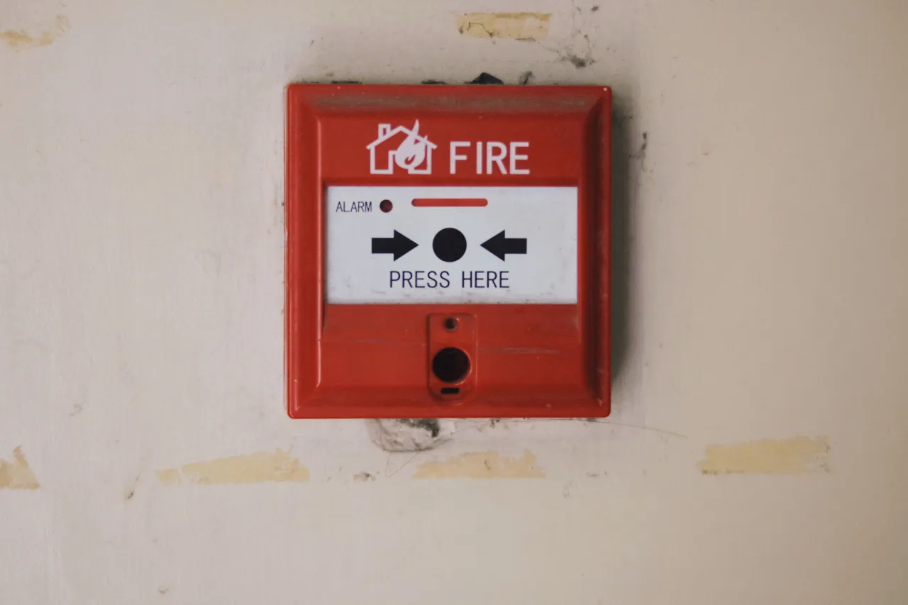 Pulsante rosso di allarme antincendio su parete
