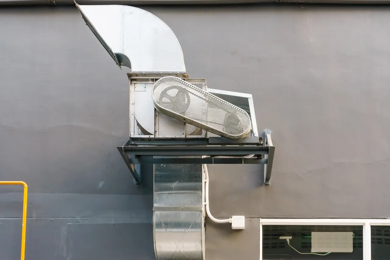 Impianto di ventilazione industriale su parete grigia