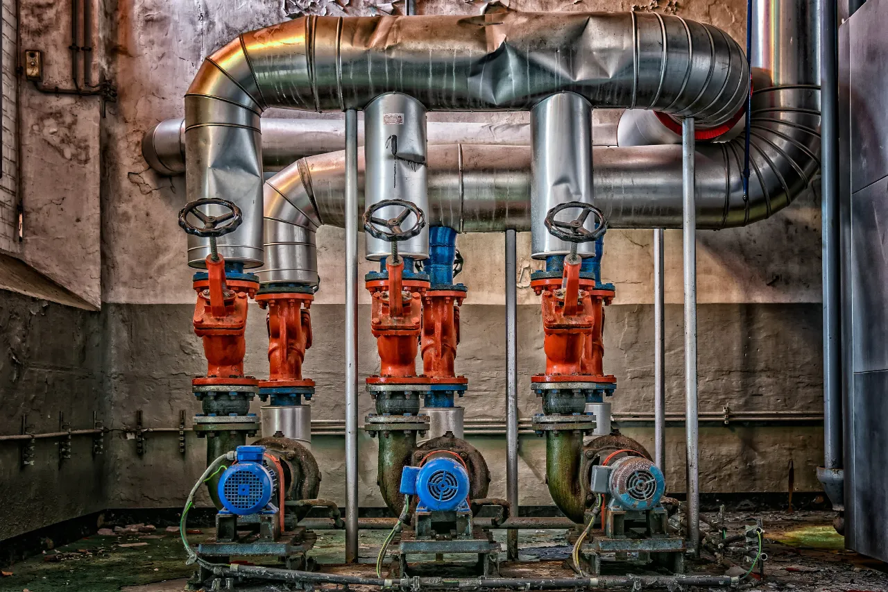 Tre pompe industriali con valvole rosse e tubazioni metalliche
