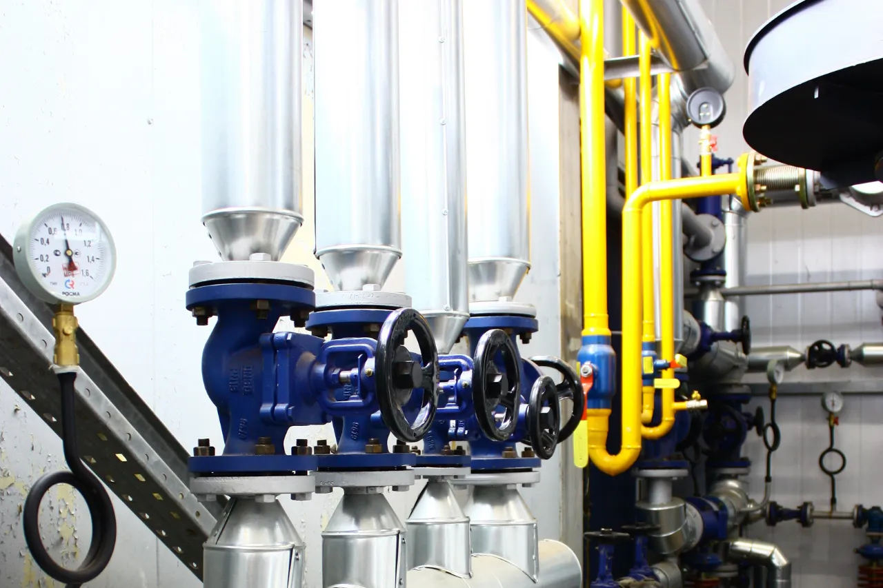 Valvole industriali blu con tubazioni gialle e manometro