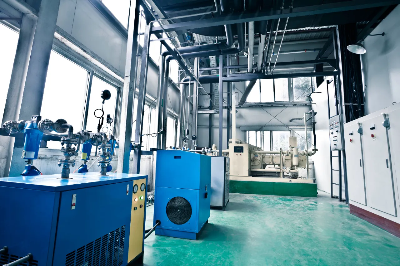 Impianto industriale con tubazioni, macchinari blu e quadri elettrici