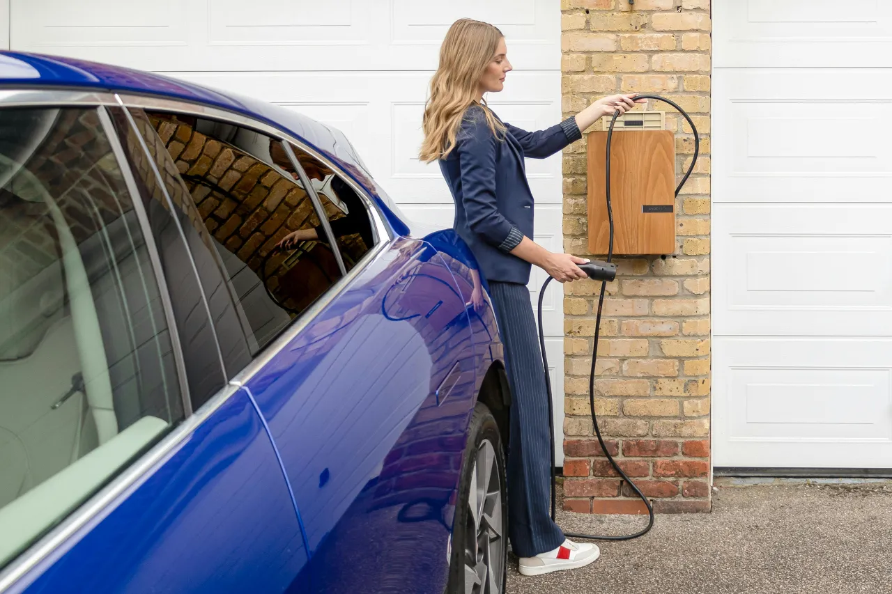 Donna collega auto elettrica a colonnina domestica