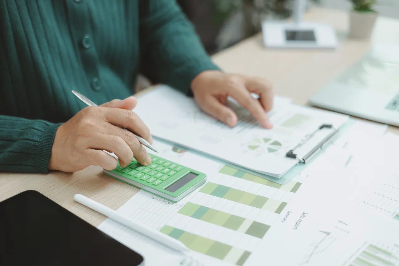 Persona calcola dati finanziari con grafici e calcolatrice