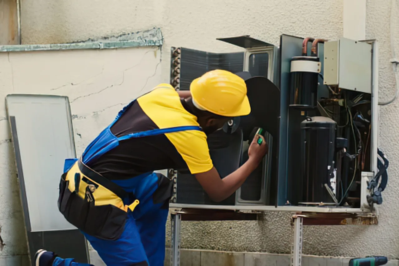 Tecnico ripara un condizionatore esterno con cacciavite