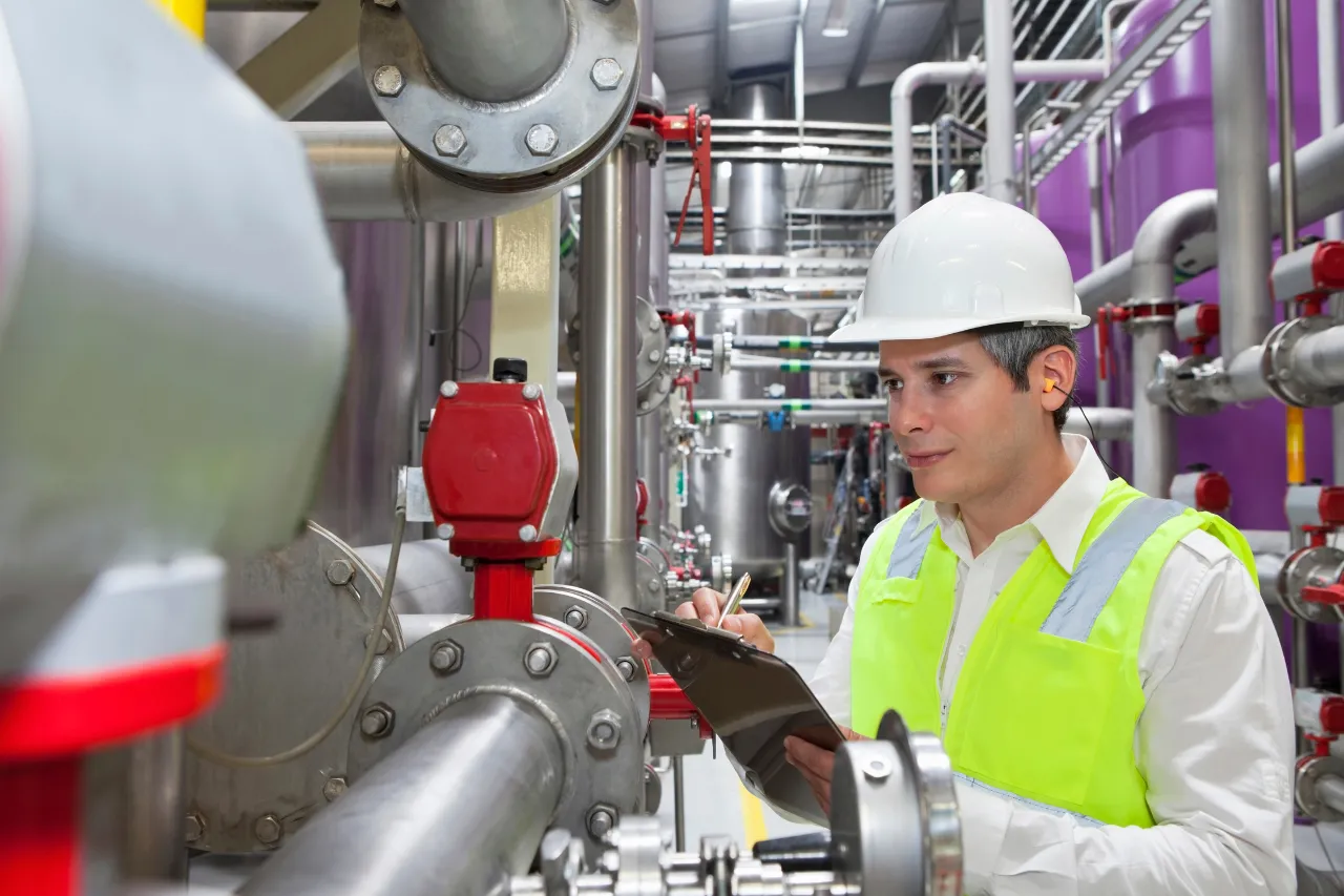 Tecnico controlla impianto industriale con tubazioni e valvole