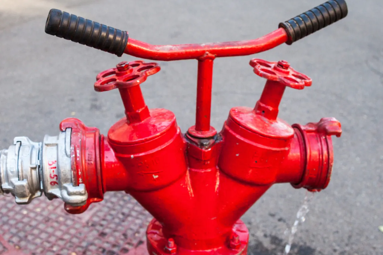 Idrante antincendio rosso con due valvole e manubrio