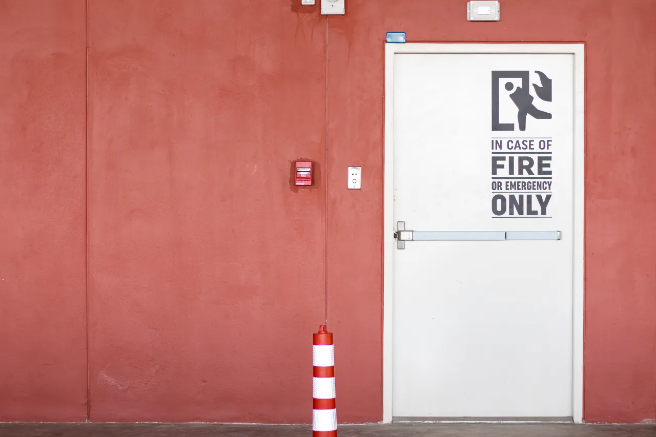 Porta antincendio bianca su parete rossa