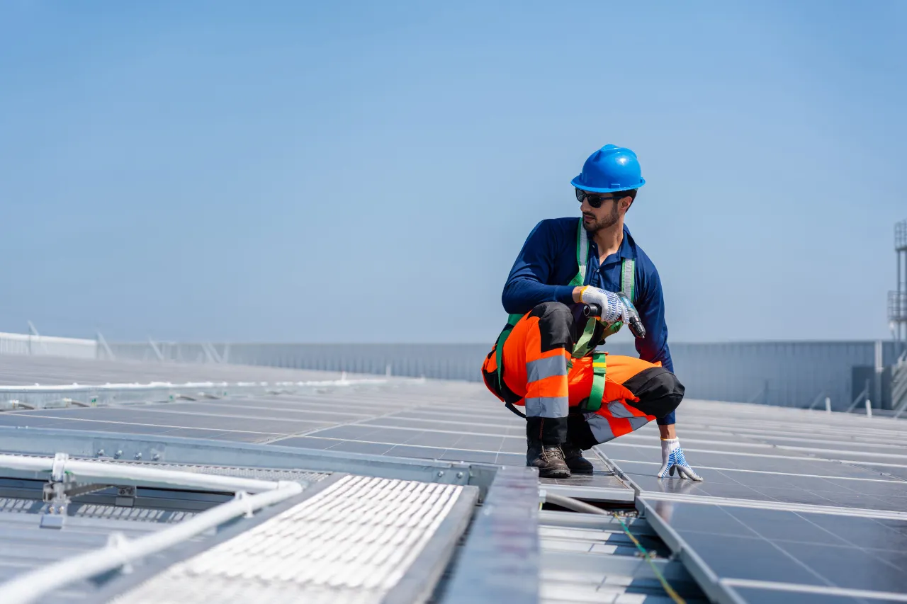 Tecnico installa pannelli solari su tetto industriale