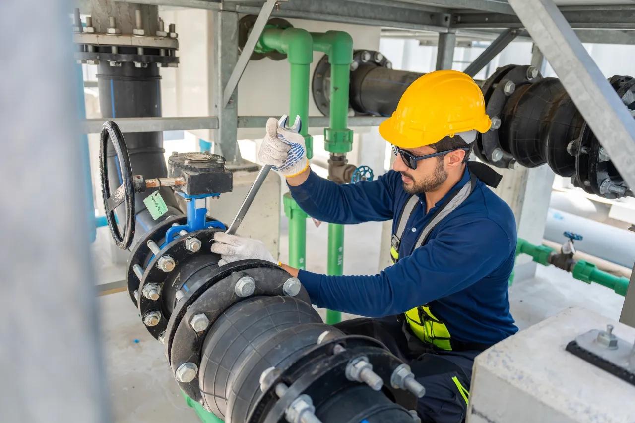 Tecnico manutentore regola una valvola in impianto industriale