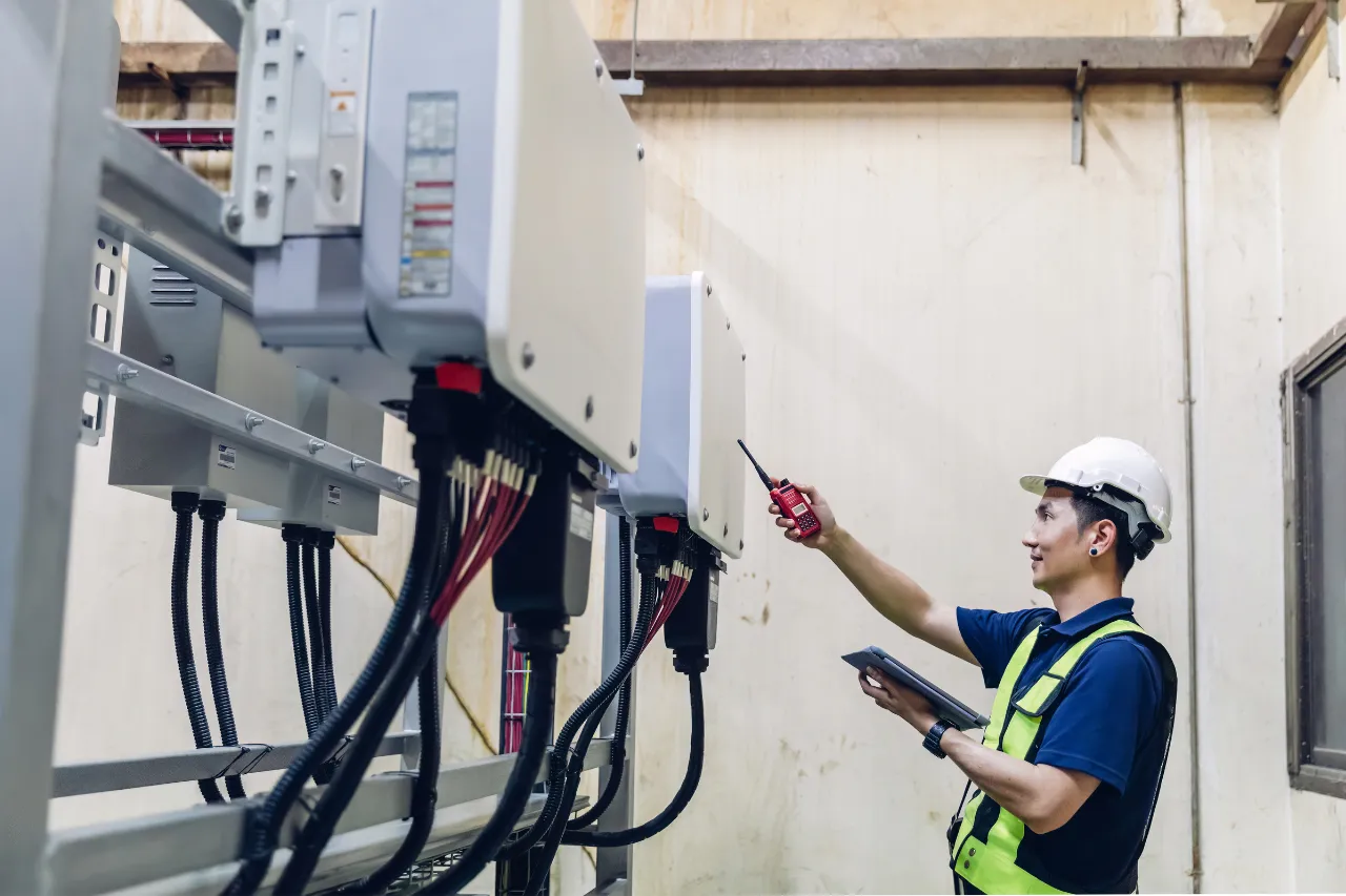 Tecnico ispeziona quadri elettrici industriali con ricetrasmittente
