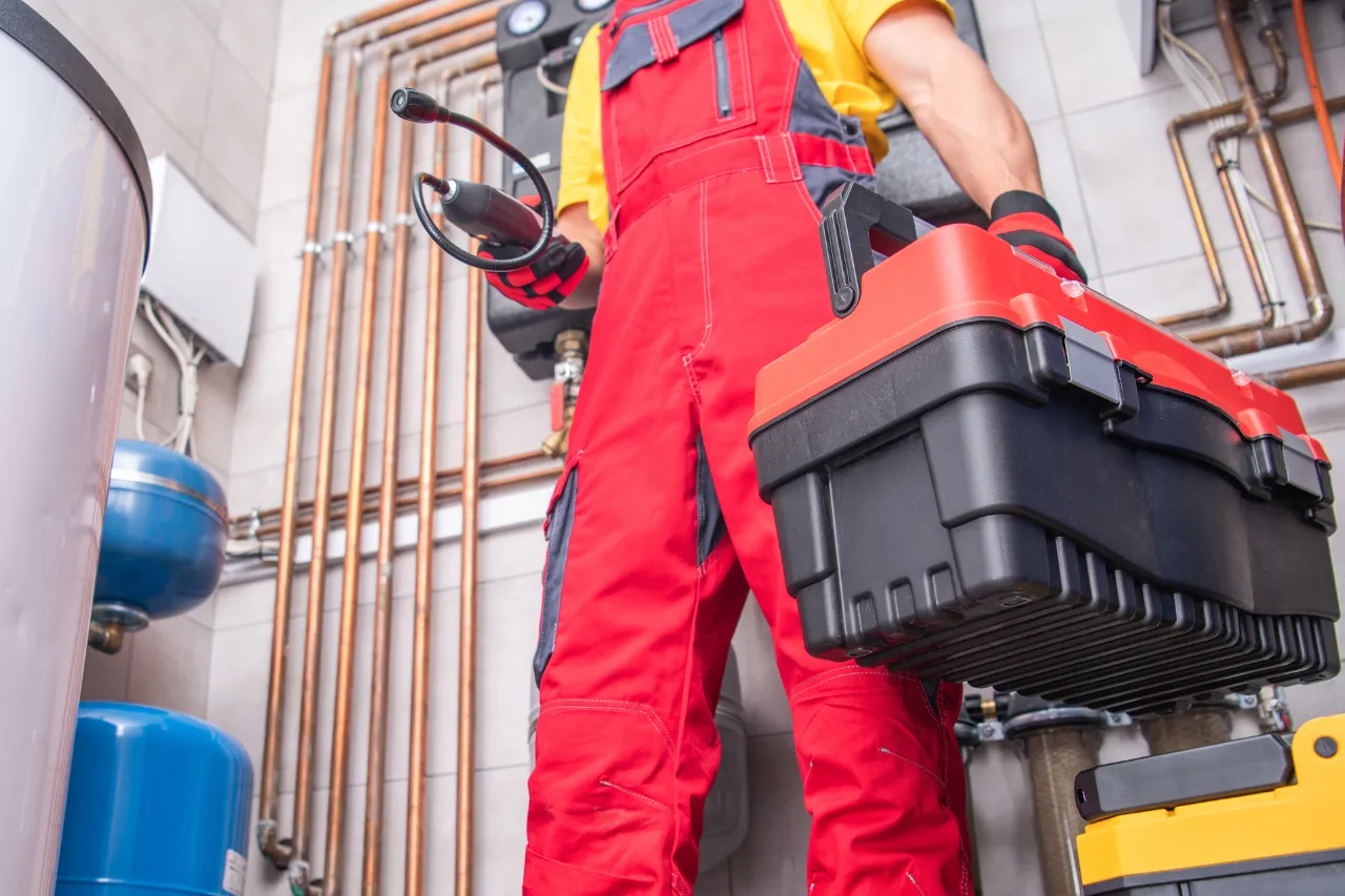 Tecnico idraulico con valigetta davanti a tubature domestiche