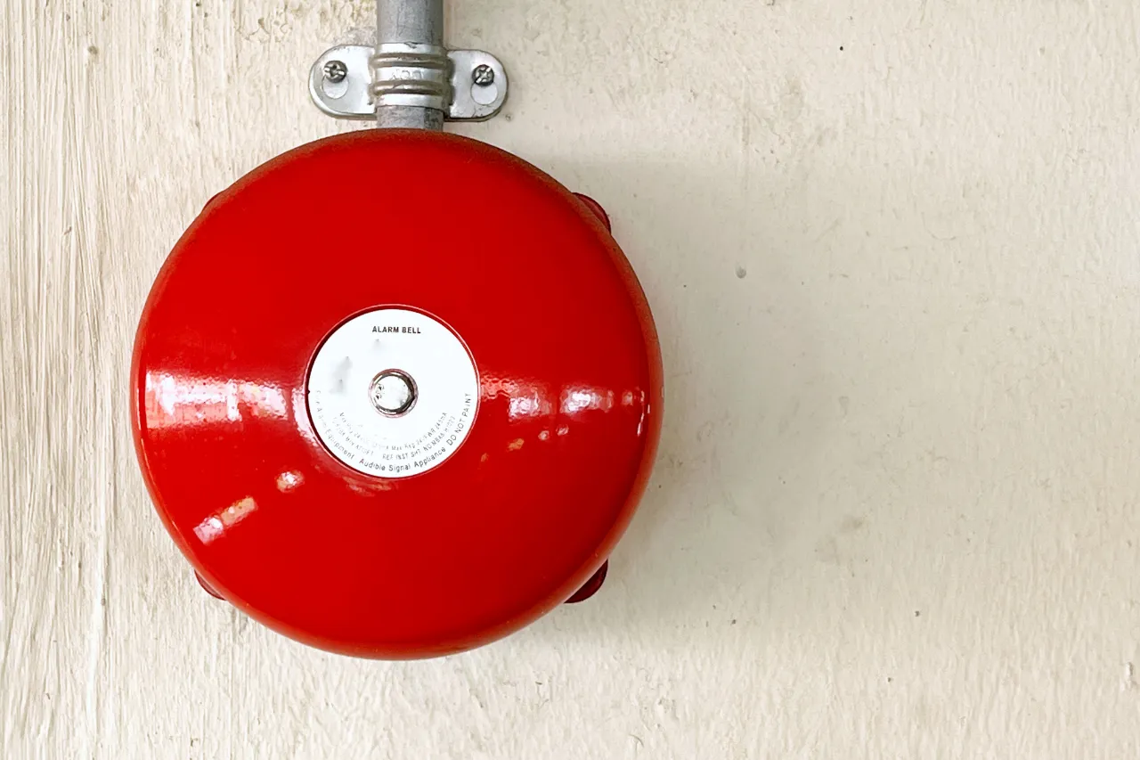 Campanello d'allarme antincendio rosso su parete chiara
