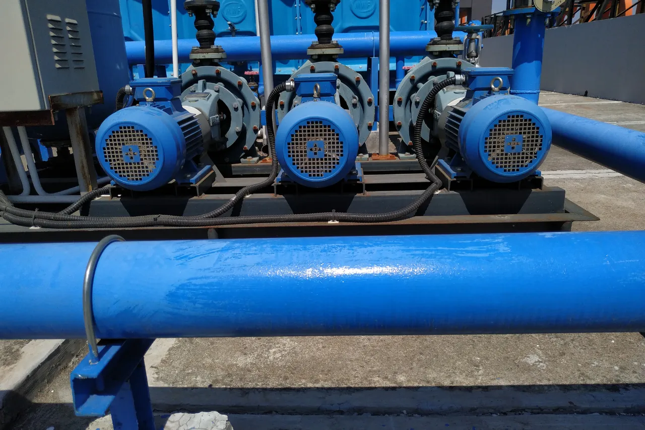 Tre pompe industriali blu collegate a tubazioni