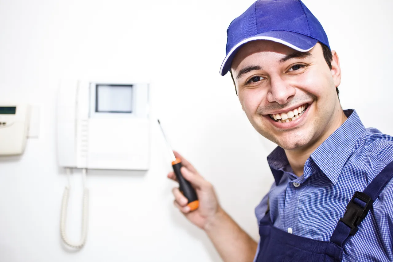 Tecnico sorridente installa citofono con cacciavite