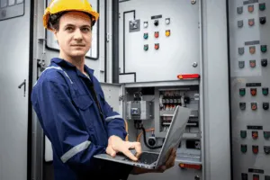 Tecnico con laptop davanti a quadro elettrico industriale