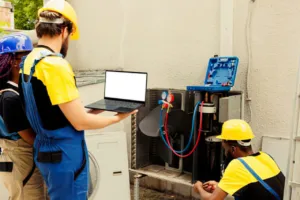 Tecnici riparano un condizionatore esterno con laptop e strumenti