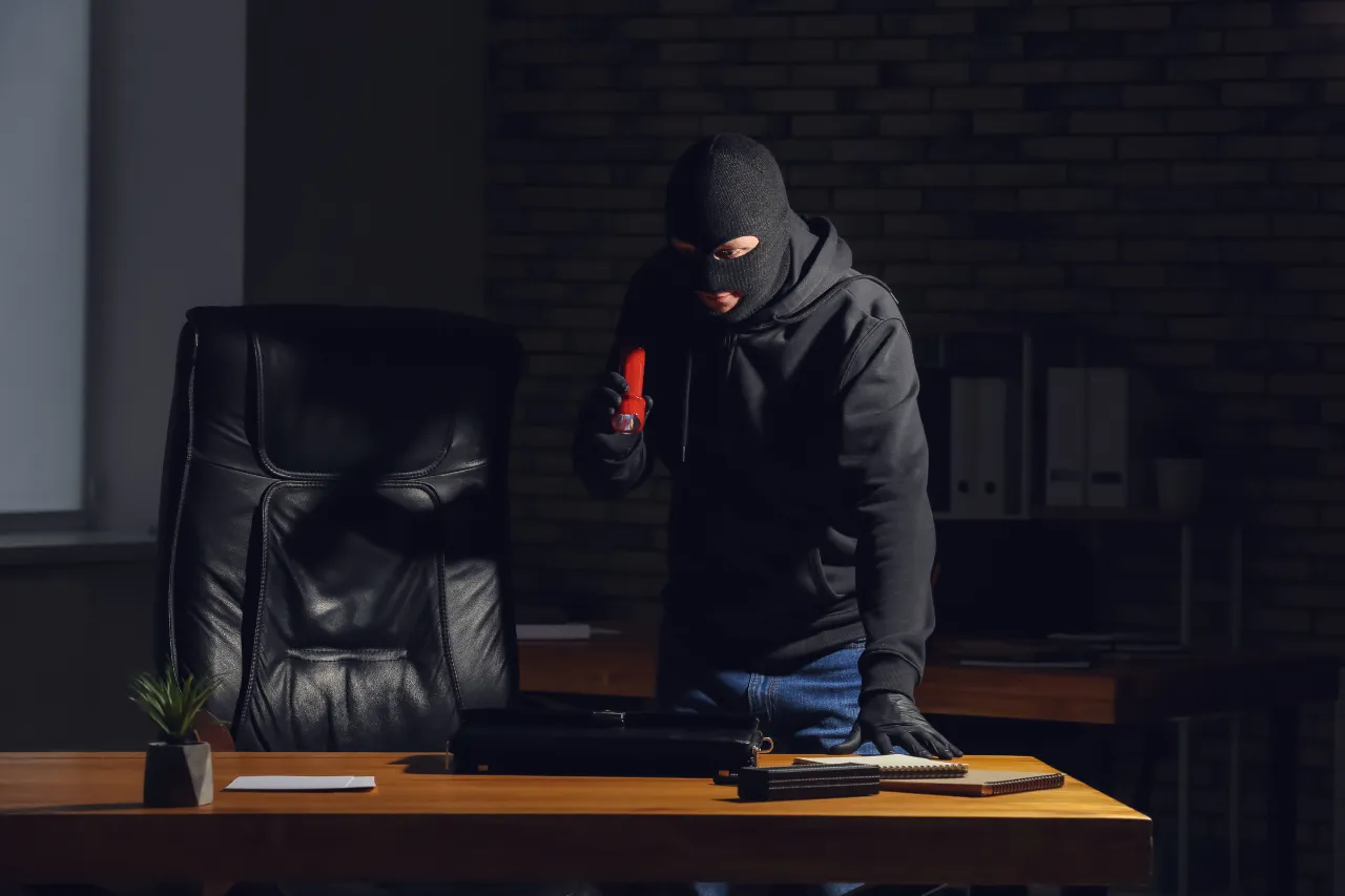 Ladro mascherato con cacciavite rosso in un ufficio